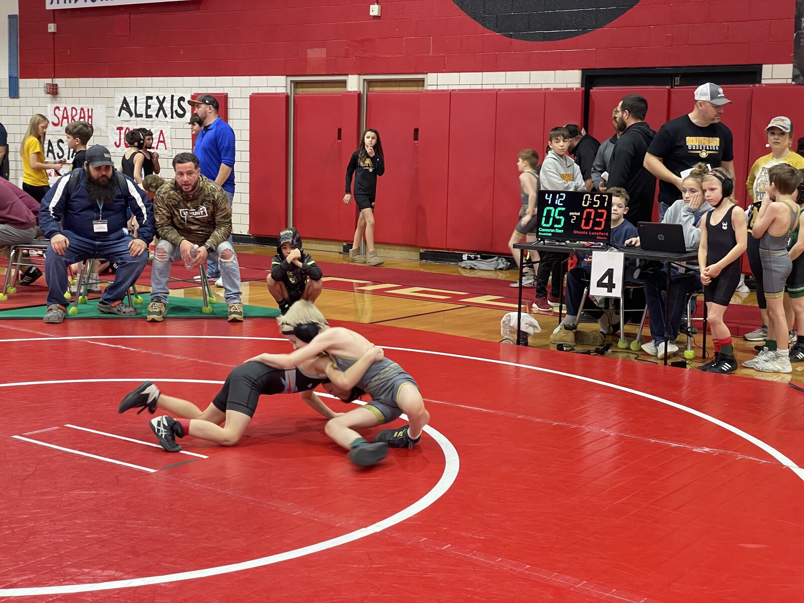 Youth wrestling match in progress with Snapdown digital scoring display showing live match data